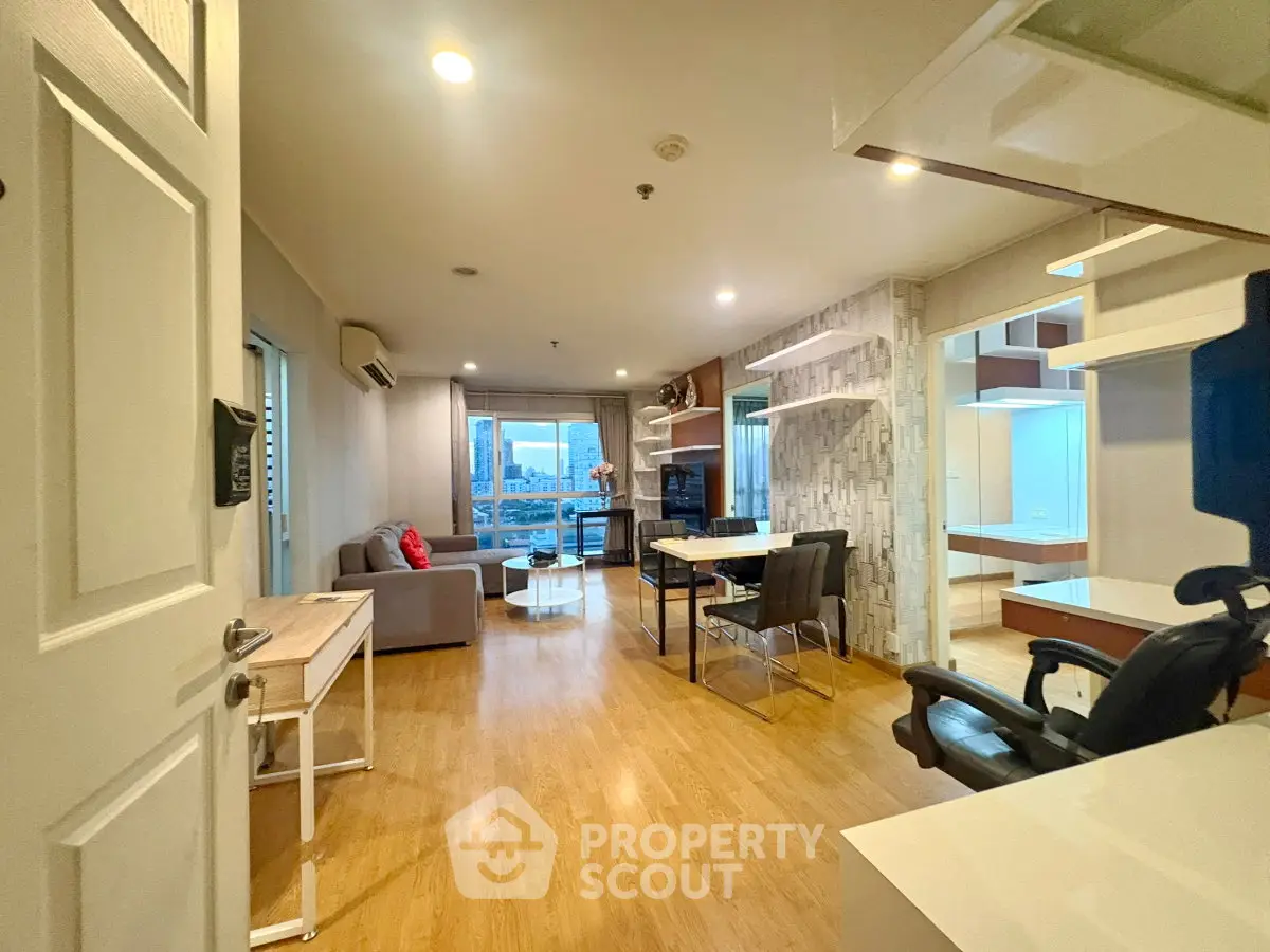 Spacious modern living room with wooden flooring and city view, perfect for urban living.