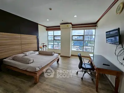 Spacious bedroom with city view, wooden flooring, and modern furnishings.