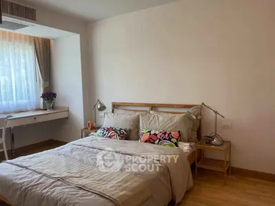 Cozy bedroom with natural light, wooden flooring, and stylish decor in a modern apartment.