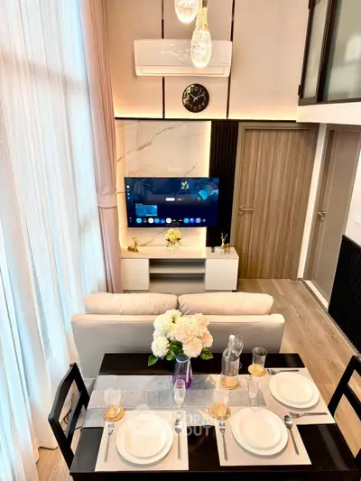 Modern living room with high ceiling, elegant decor, and dining area in a stylish apartment.