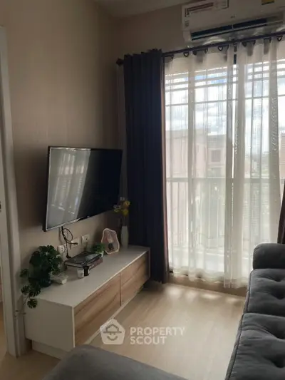 Cozy living room with modern TV setup and natural light from large window.