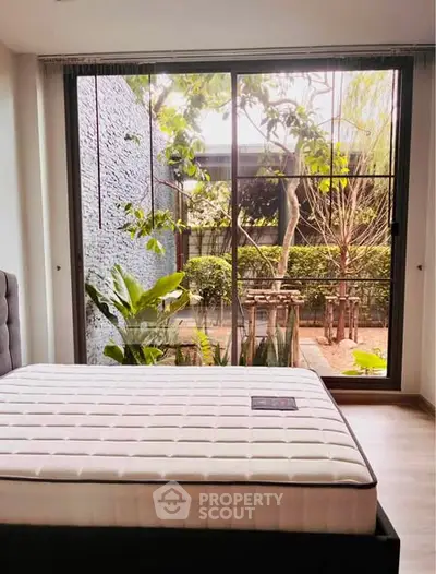 Spacious bedroom with large window overlooking lush garden, perfect for nature lovers seeking tranquility.