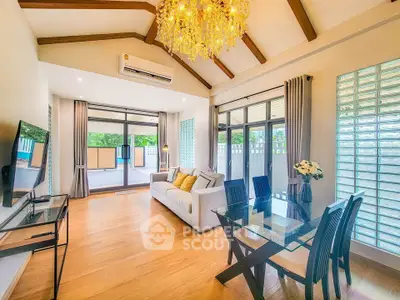 Spacious living room with elegant chandelier and modern decor, featuring large windows and wooden flooring.