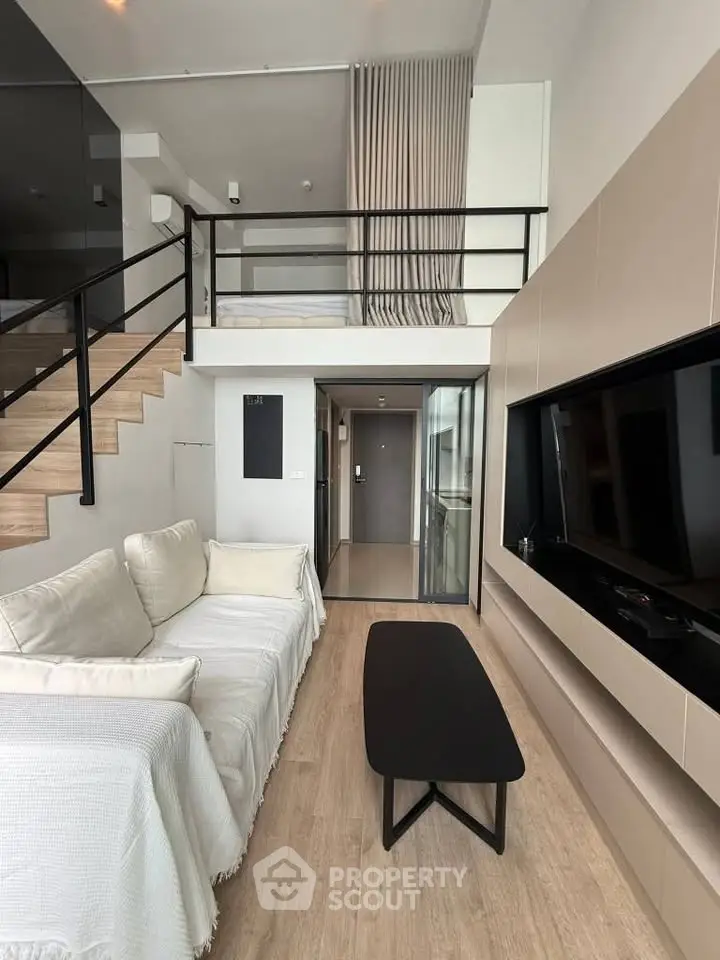 Modern loft-style living room with mezzanine, sleek furniture, and large TV unit.