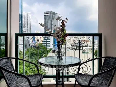 Charming balcony with city view, featuring elegant wrought iron railing and cozy seating area.