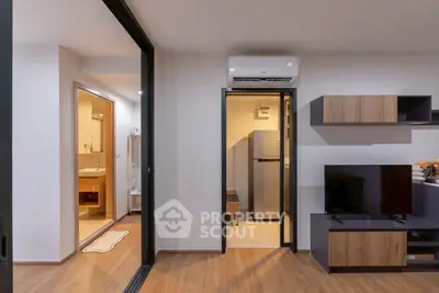 Modern apartment interior with open living area and kitchen, featuring sleek design and wooden flooring.