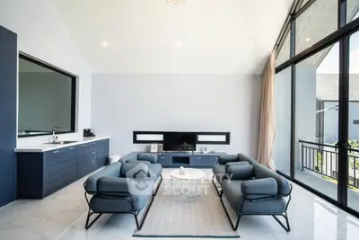 Modern living room with sleek furniture and large windows opening to a balcony.
