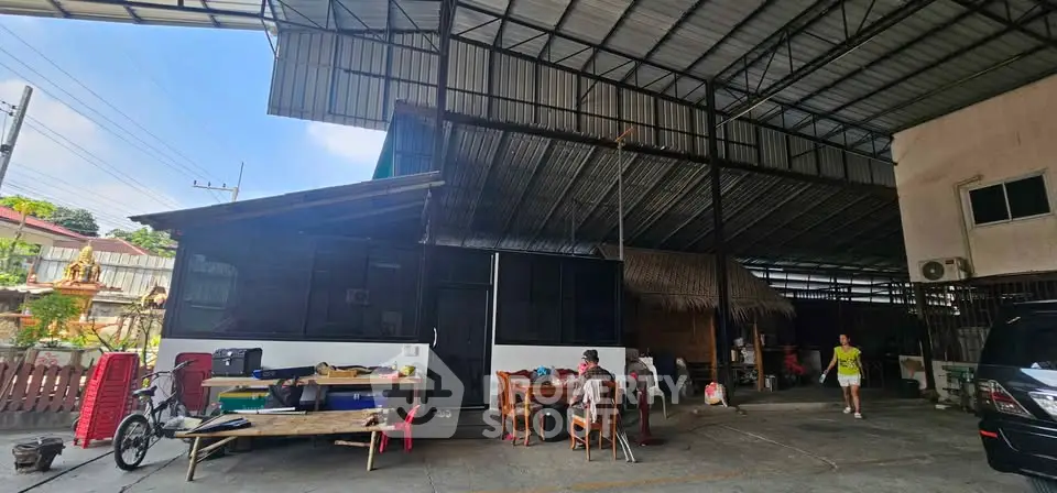 Spacious outdoor area with covered roof and seating, ideal for gatherings and activities.