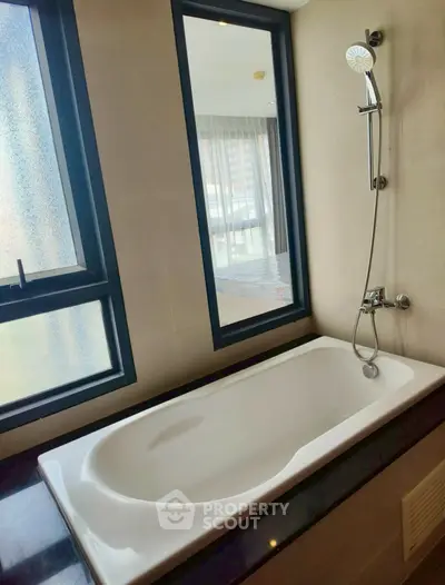 Luxurious bathroom with modern bathtub and large windows offering natural light.