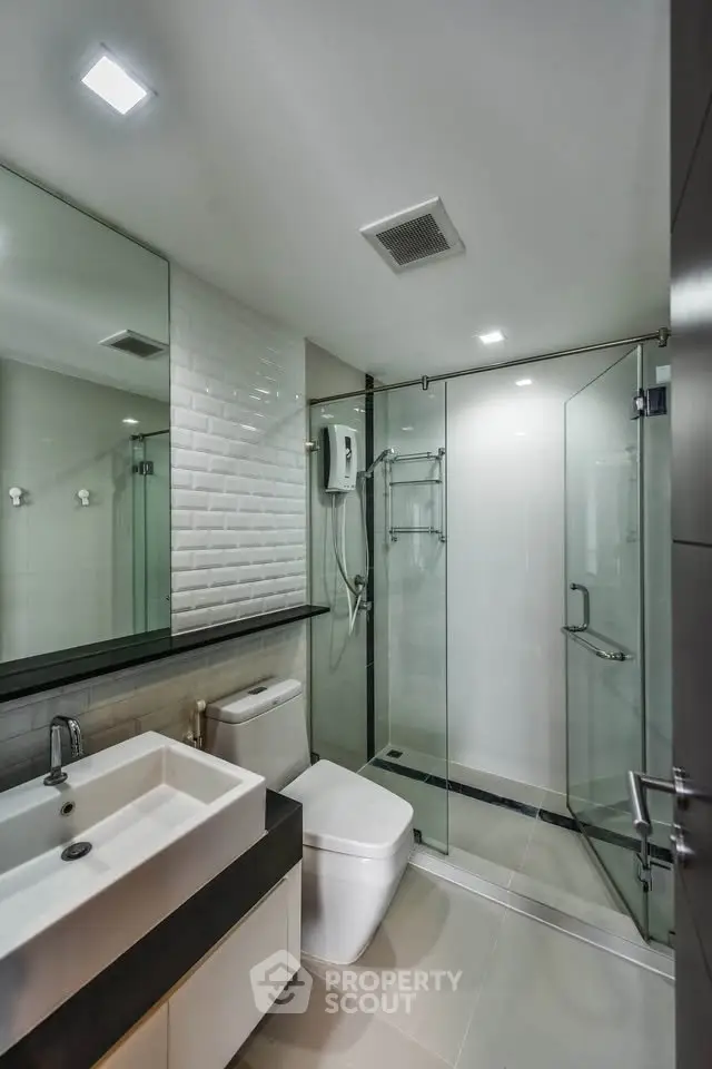 Modern bathroom with glass shower and sleek fixtures in contemporary apartment.