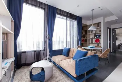 Modern living room with stylish blue sofa, large windows, and elegant decor in a contemporary apartment.