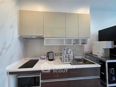 Modern kitchen with sleek cabinetry, induction cooktop, and stainless steel sink in a contemporary apartment.