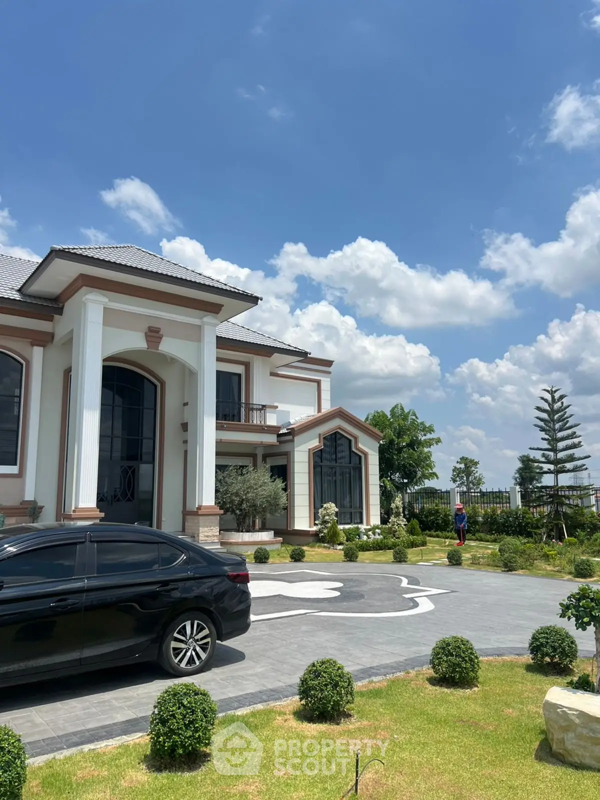 Luxurious mansion with elegant architecture and manicured garden under a clear blue sky.