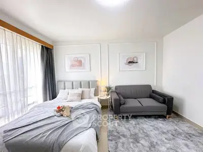 Modern bedroom with stylish decor, cozy bed, and elegant sofa in a bright, airy space.