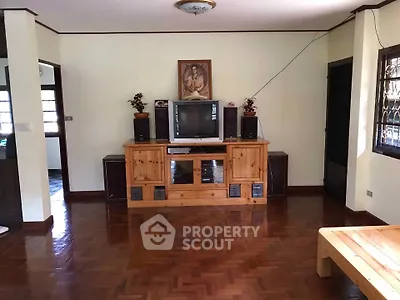 Spacious living room with wooden flooring and classic entertainment center.