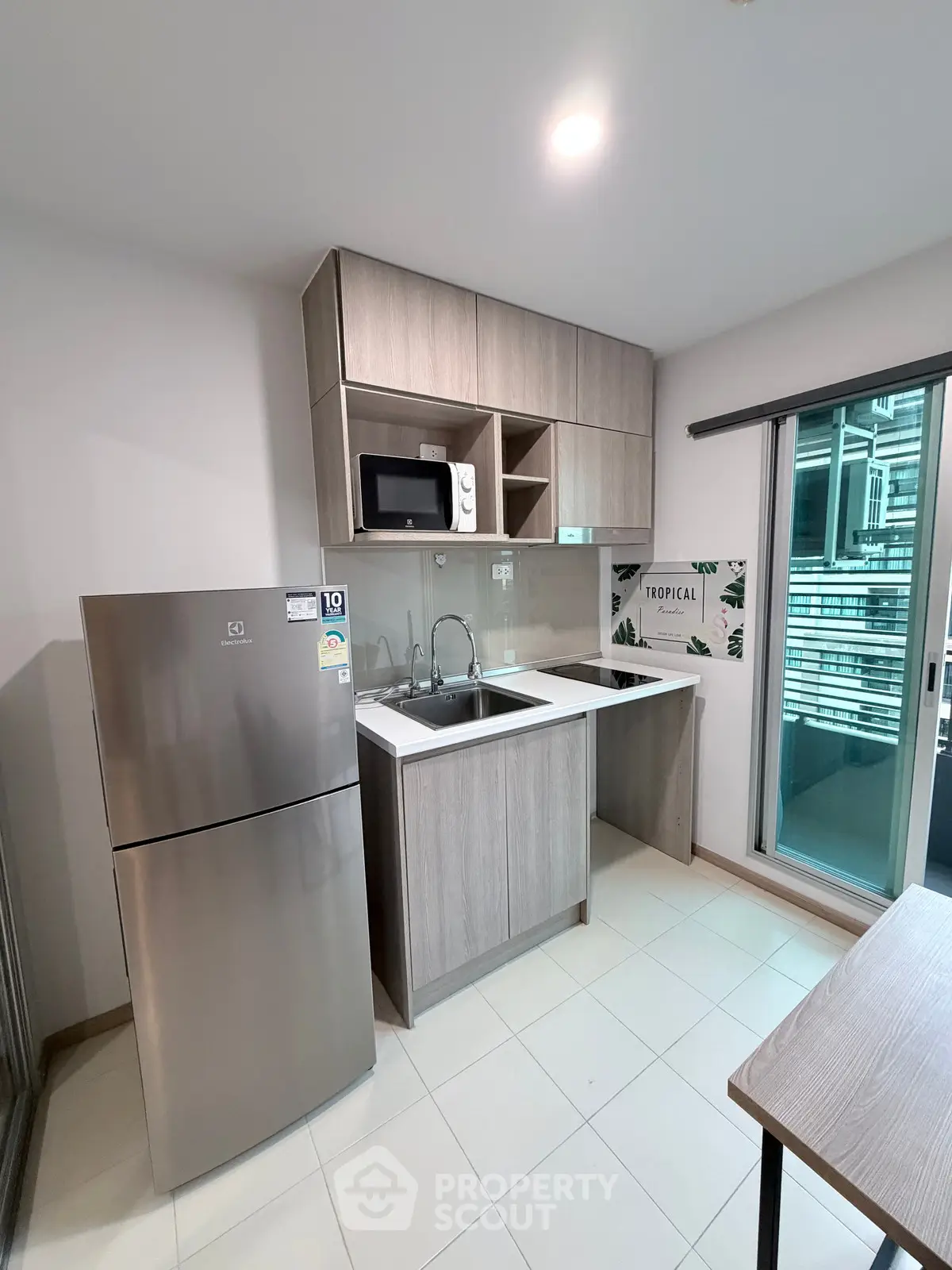 Modern kitchen with sleek cabinetry, stainless steel fridge, and microwave in a contemporary apartment.