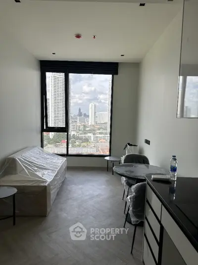 Modern apartment with city view, featuring minimalist furniture and large windows.