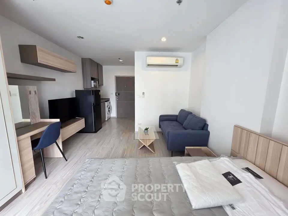 Modern studio apartment with open layout, featuring a cozy living area, compact kitchen, and stylish furnishings.