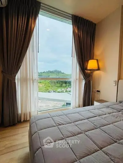 Cozy bedroom with large window offering scenic views and elegant curtains, perfect for relaxation.