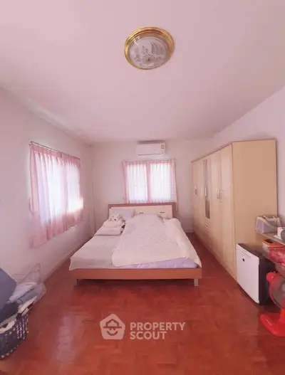 Spacious bedroom with natural light, wooden flooring, and ample storage in a cozy home.