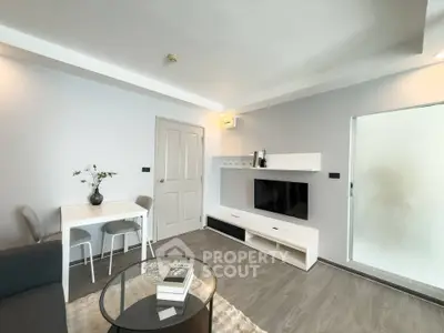 Modern living room with sleek furniture and minimalist decor, featuring a wall-mounted TV and cozy seating area.