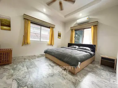 Spacious bedroom with modern decor and large windows for natural light.