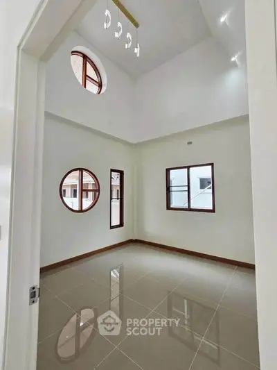 Spacious modern room with high ceiling and unique circular windows, perfect for customization.