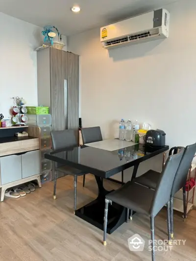 Modern dining area with sleek black table and chairs, featuring air conditioning and stylish storage solutions.