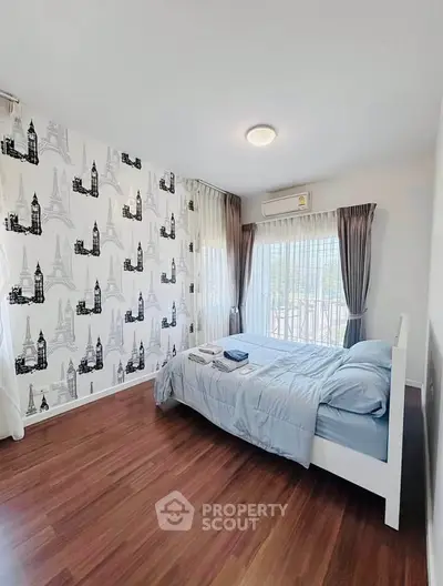 Stylish bedroom with city-themed wallpaper and large windows for natural light.