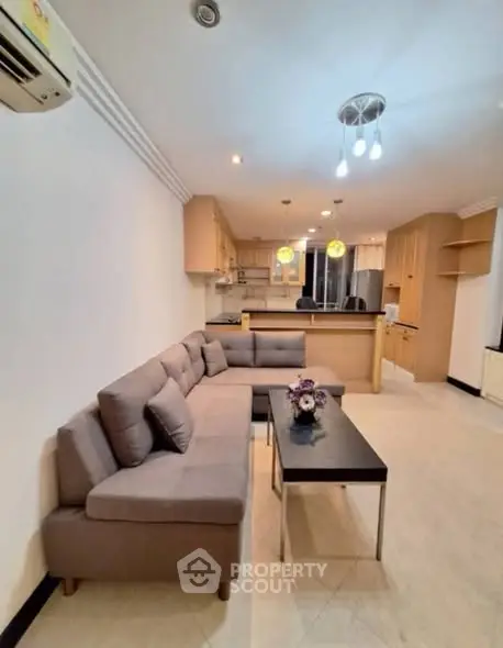 Spacious living room with modern kitchen in open layout, featuring cozy sofa and stylish lighting.