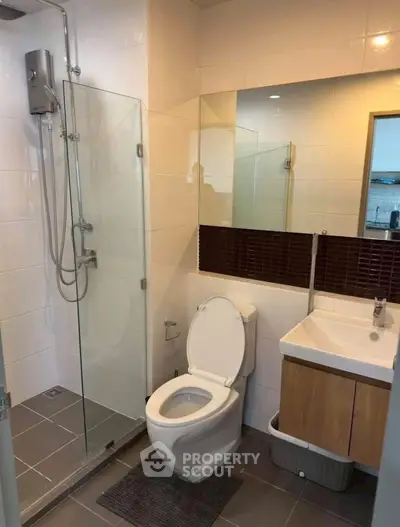 Modern bathroom with glass shower and sleek vanity in a contemporary apartment.