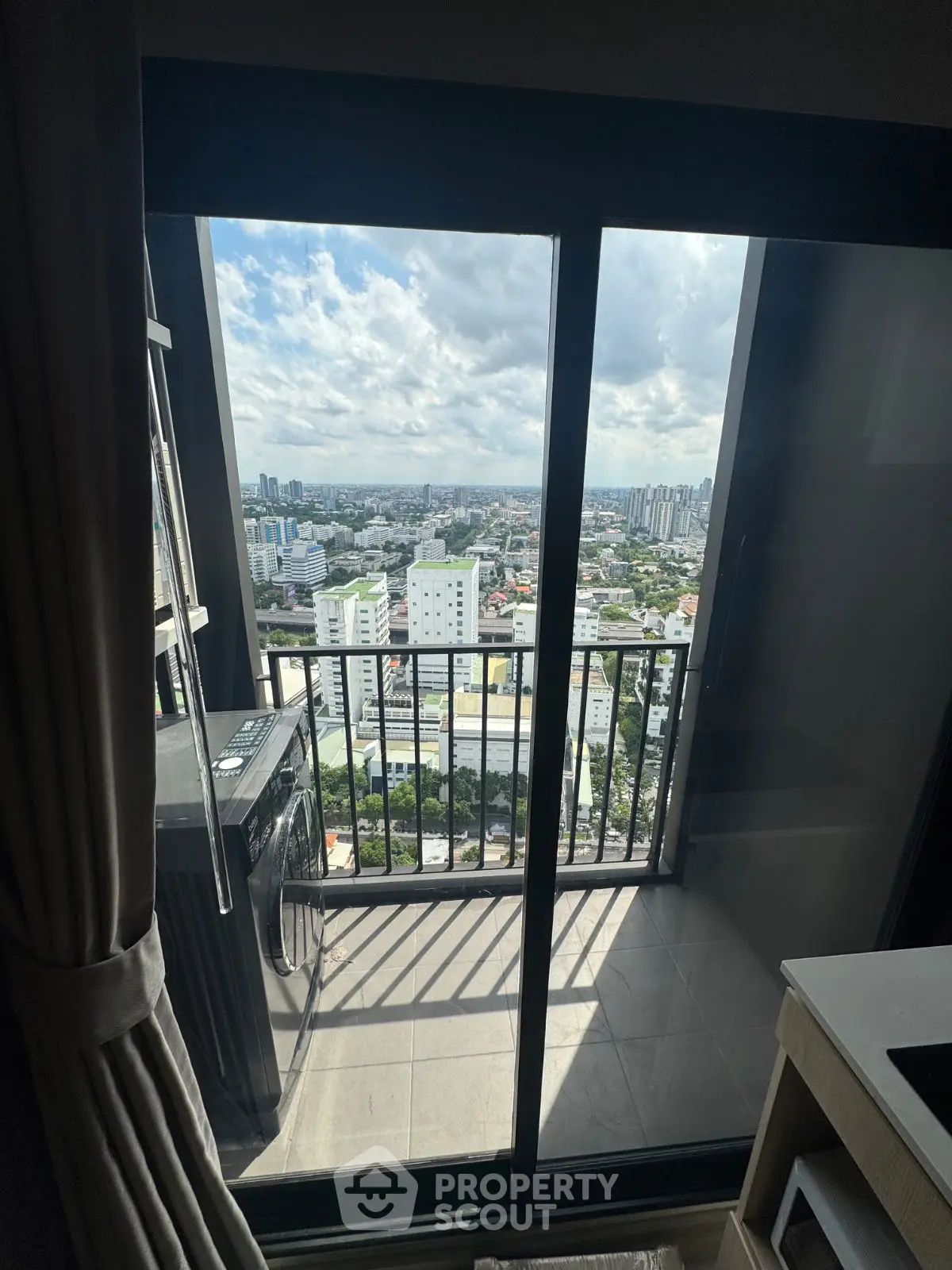 Stunning high-rise balcony view with cityscape and modern washing machine.