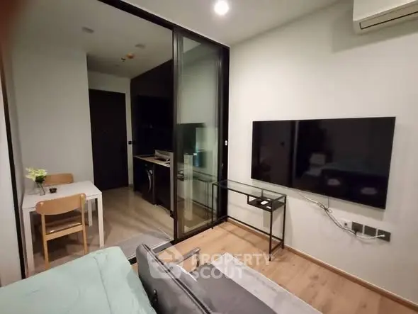 Modern living room with glass partition and sleek TV setup in stylish apartment.
