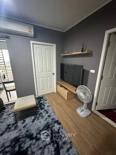 Cozy living room with modern decor, featuring a TV, fan, and stylish shelving.