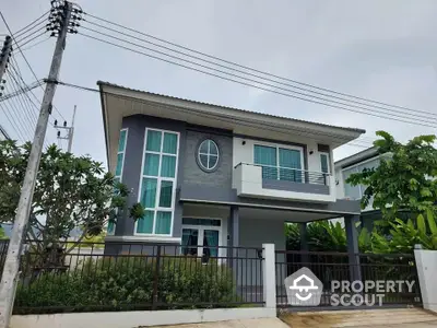 Modern two-story house with large windows and balcony in lush green setting