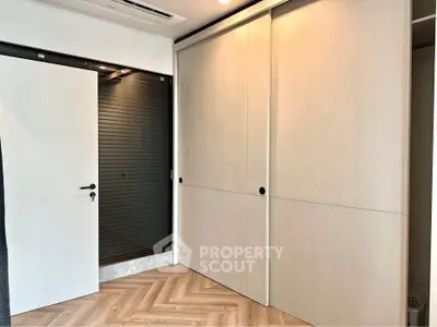 Modern interior with sleek sliding closet doors and herringbone wood flooring