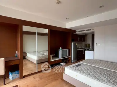 Spacious bedroom with mirrored wardrobe and kitchenette, ideal for modern living.