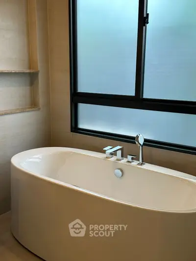 Luxurious bathroom with modern freestanding bathtub and frosted window for privacy.