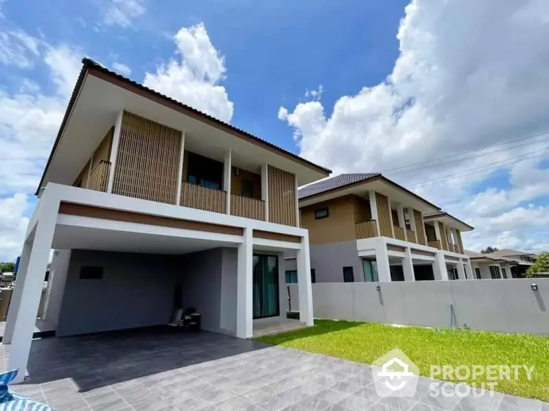 Modern two-story house with spacious driveway and lush green lawn under a clear blue sky.