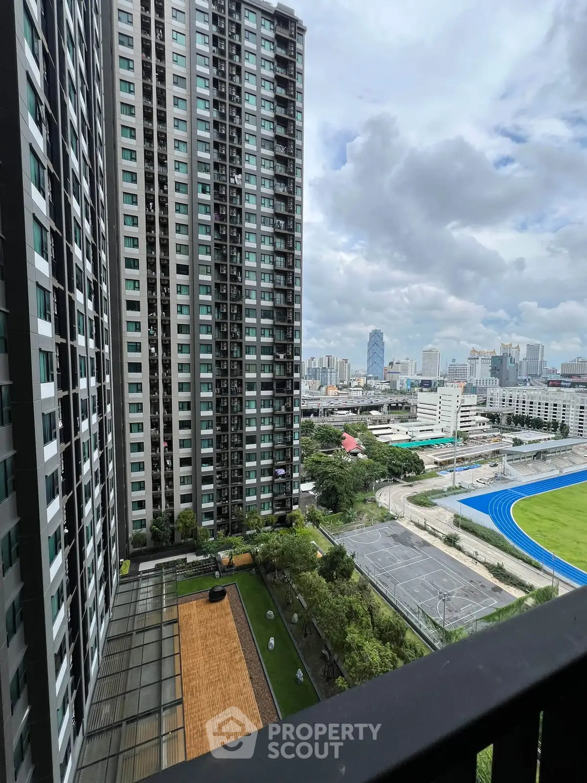 Stunning cityscape view from high-rise balcony overlooking urban skyline and sports field.