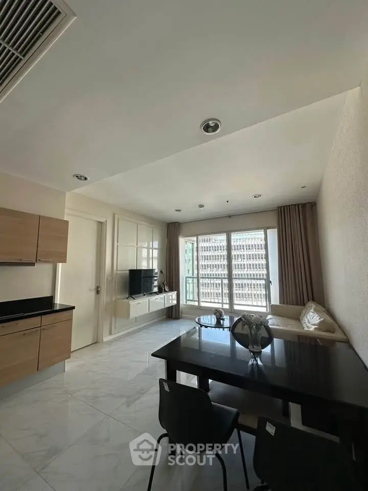 Modern living room with sleek furniture and large windows offering city views.