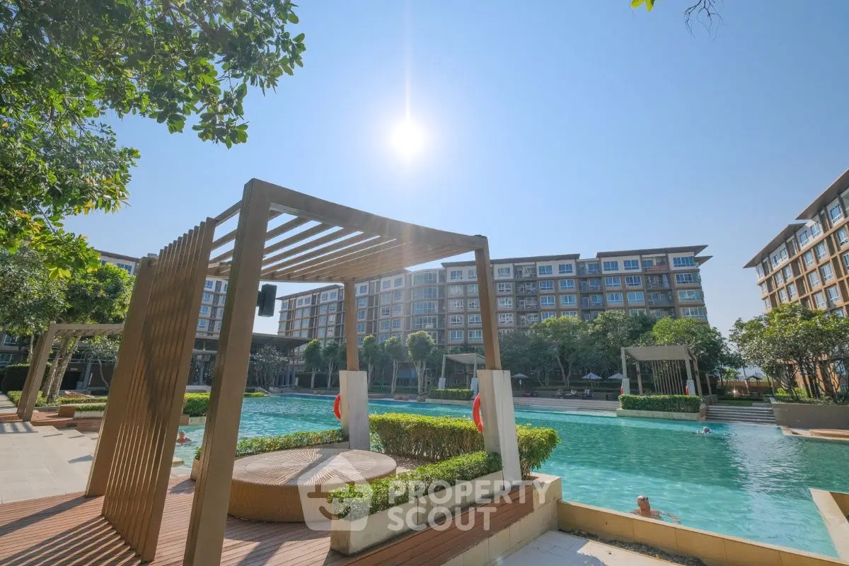 Luxurious apartment complex with stunning pool and modern architecture under clear blue sky.