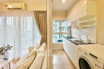 Modern apartment with open kitchen and cozy living area, featuring a washing machine and large windows.