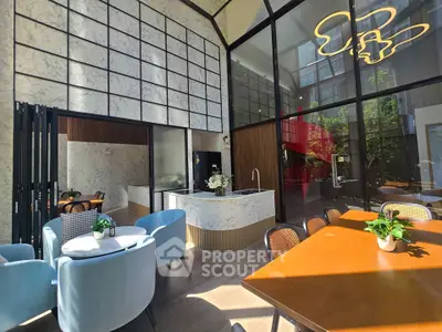 Modern living room with high ceilings and stylish furniture in a sunlit space.