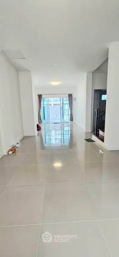 Spacious modern living room with glossy tiled floors and large windows for natural light.