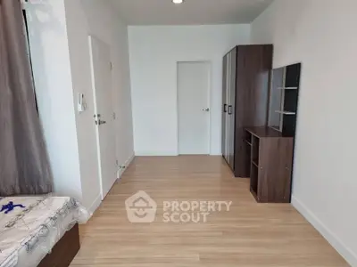 Spacious bedroom with wooden flooring and modern furniture in a minimalist design.