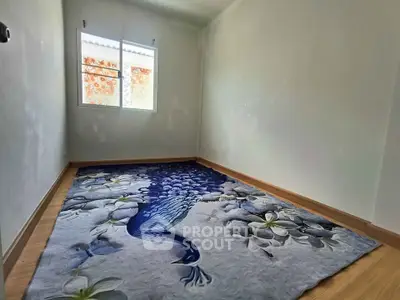 Minimalist bedroom with unique peacock-themed carpet and natural light.