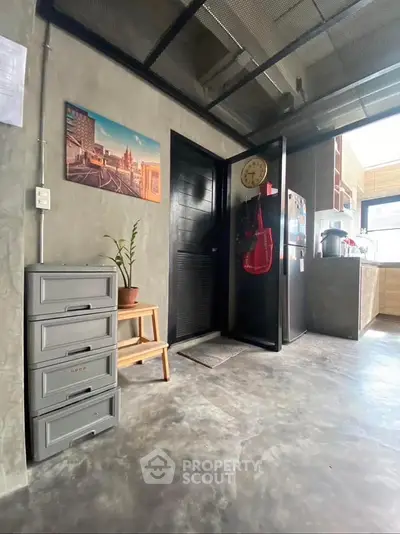Modern industrial-style kitchen with concrete floors and sleek black door