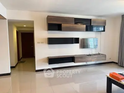 Spacious modern living room with sleek wall-mounted shelves and TV, ideal for contemporary living.