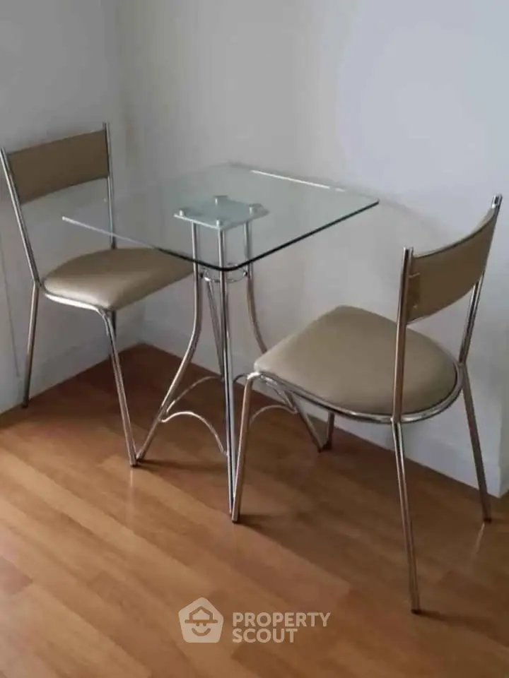 Modern dining area with glass table and sleek metal chairs on wooden floor